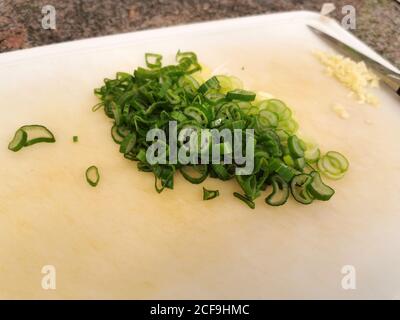 Primo piano di cipolla verde tagliata finemente e cotta per la lattuga giace sul bordo Foto Stock