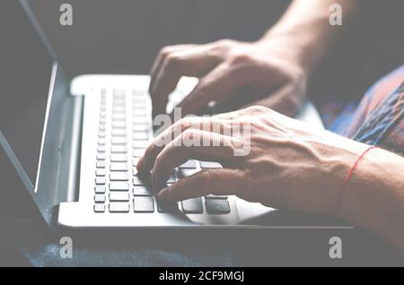 Un uomo si siede su un davanzale con un laptop nelle sue mani e le opere Foto Stock