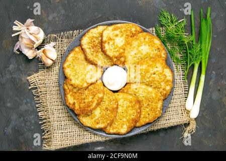 Frittelle di patate con salsa decorata con burlap, cipolla verde e aglio. Viste dall'alto, primo piano Foto Stock