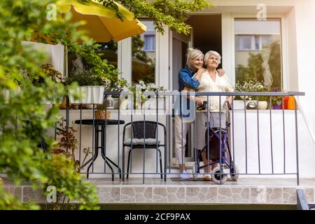 Donna anziana e sua figlia adulta in piedi sul balcone Foto Stock