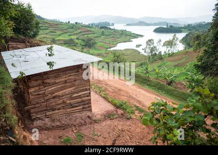 Uganda - 26 novembre 2016: Da sopra magnifico scenario di campagna con piccoli campi coltivati e villaggio solitario tra colline con verde erba lussureggiante e fitte foreste Foto Stock