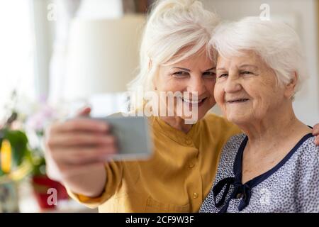 La donna anziana e la figlia adulta che utilizzano lo smartphone insieme Foto Stock
