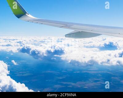ala di aeroplano in cielo blu sopra le nuvole di pioggia e la terra durante il volo il giorno d'estate Foto Stock