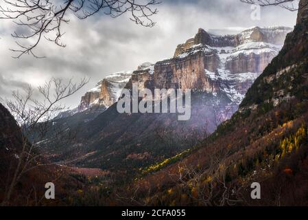 Splendida vista sulla cima della montagna coperta di neve paesaggio montano circondato da foresta in giorno di coperto in autunno Foto Stock