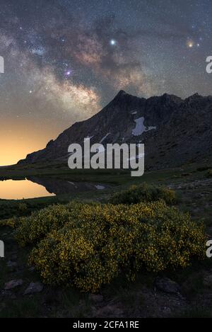 Incredibile vista panoramica della catena montuosa sotto l'incredibile notte stellata cielo con modo lattiginoso e infrangere i raggi del sole nascente da dietro le montagne in inverno sera Foto Stock