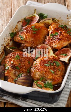 Cosce di pollo speziate cotte con fichi freschi e primo piano in una teglia sul tavolo. Verticale Foto Stock