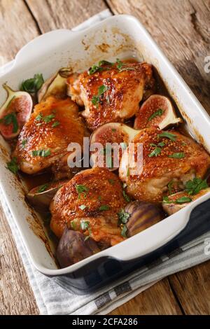 Deliziose cosce di pollo balsamico al forno con fichi ed erbe da vicino in una teglia sul tavolo. Verticale Foto Stock