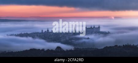 Vista aerea della città antica e medievale Alcazar de Toledo palazzo in nebbia in una coloratissima pausa giorno Foto Stock