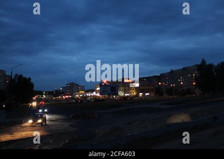 trattore in città per lavori di riparazione di lavori di costruzione in città di notte in serata al tramonto nel scuro Foto Stock