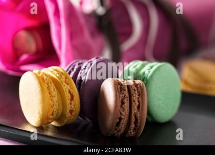 Primo piano di deliziosi macaron francesi colorati con vari ripieni posti su bancone di legno con sfondo sfocato Foto Stock