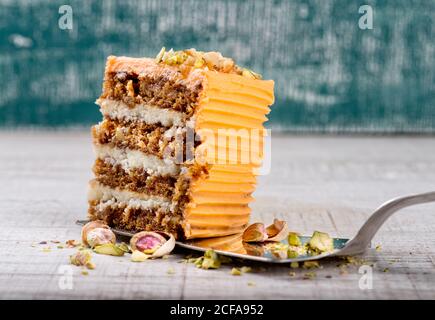 Torta server con pezzo di deliziosa torta di carote con pistacchi su tavolo di legno Foto Stock