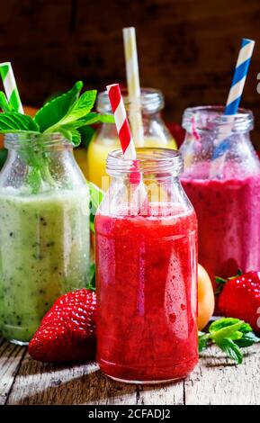 Frullati di frutta con paillette colorate in bottiglie di vetro, fuoco selettivo Foto Stock