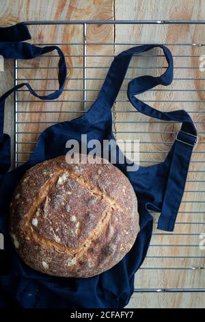 Vista dall'alto della deliziosa focaccia rotonda marrone di pane di pasta acida su grembiule nero dal forno in cucina Foto Stock