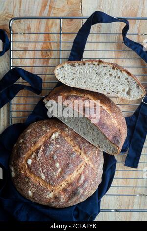 Vista dall'alto della deliziosa focaccia rotonda marrone di pane di pasta acida su grembiule nero dal forno in cucina Foto Stock