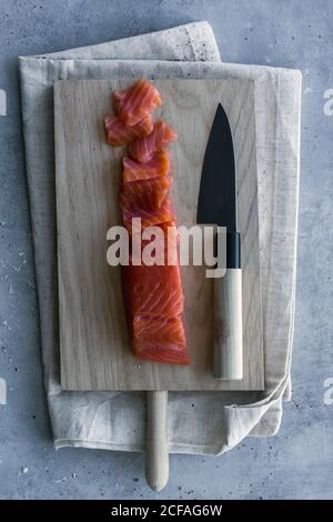 Dall'alto appetitoso salmone fresco a fette su tavola con legno tavola e coltello Foto Stock