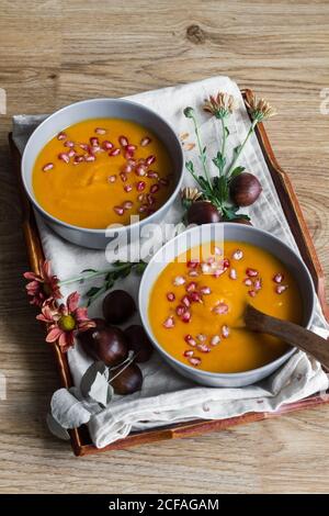 Da sopra arrangiamento con zuppa di zucca cremosa con castagne e. semi di melograno in ciotola con cucchiaio Foto Stock