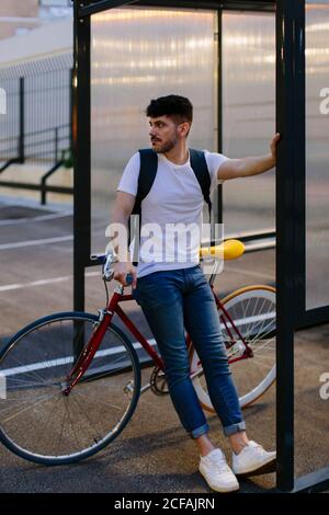 Giovane caucasico seduto in bicicletta in un parcheggio all'ultima ora del giorno. Foto Stock
