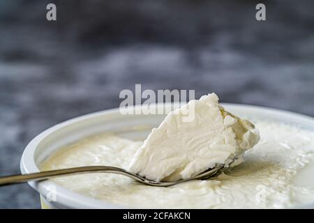 Yogurt / yogurt di pecora istantaneo con cucchiaio in tazza di plastica. Pronto a mangiare. Foto Stock
