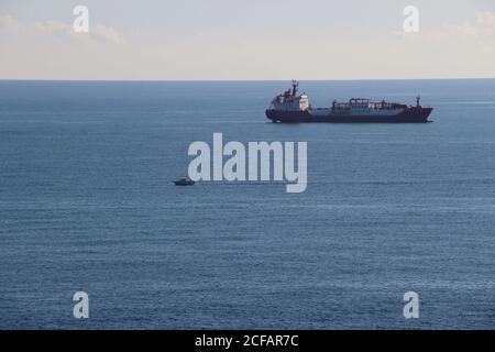 Tessa Kosan petroliera GPL all'ancora al largo della costa con Una piccola barca da pesca che passa di fronte Santander Cantabria Spagna Foto Stock