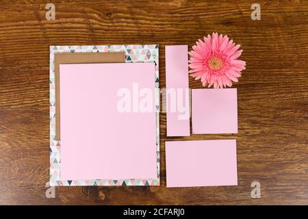 Foglio rosa di carte circondato da un fiore su legno tabella Foto Stock