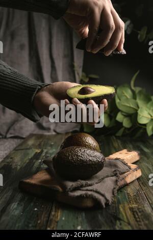 anonima persona mani taglio avocado a metà per preparare guacamole Foto Stock