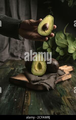 anonima persona mani taglio avocado a metà per preparare guacamole Foto Stock