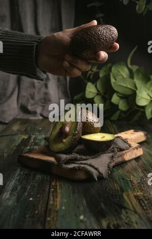 anonima persona mani taglio avocado a metà per preparare guacamole Foto Stock