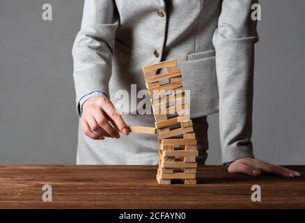 Uomo d'affari che rimuove il blocco di legno dalla torre Foto Stock