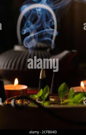 Composizione del cono di incenso e delle candele di tè bruciate su legno vassoio con teiera orientale preparato per il relax e la meditazione Foto Stock