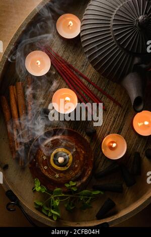 Composizione del cono di incenso e delle candele di tè bruciate su legno vassoio con teiera orientale preparato per il relax e la meditazione Foto Stock