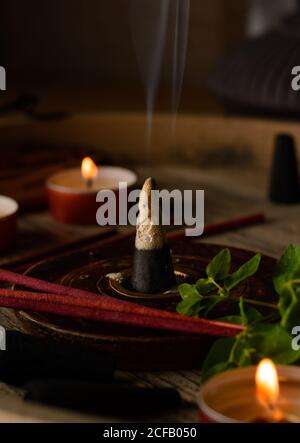 Composizione del cono di incenso e delle candele di tè bruciate su legno vassoio con teiera orientale preparato per il relax e la meditazione Foto Stock