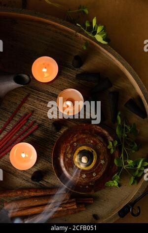 Composizione del cono di incenso e delle candele di tè bruciate su legno vassoio con teiera orientale preparato per il relax e la meditazione Foto Stock