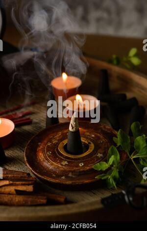 Composizione del cono di incenso e delle candele di tè bruciate su legno vassoio con teiera orientale preparato per il relax e la meditazione Foto Stock