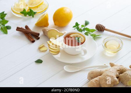 Ingredienti per il tè allo zenzero con limone, miele, menta, cannella su tavola bianca Foto Stock