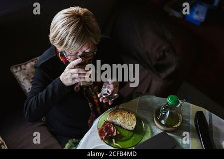 Donna attraente Senior che prende il farmaco dalla scatola della pillola prima della colazione Foto Stock