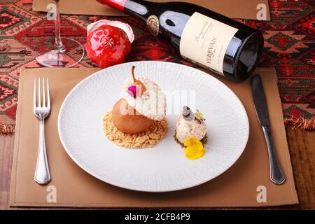 Par dessert in camicia con pralina e gelato alla noci. Servito con una bottiglia di vino melograno. Foto Stock