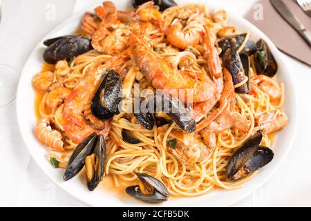 Spaghetti con frutti di mare. Spaghetti piccanti con cozze, vongole, calamari, gamberi, granchio, in salsa di pomodoro primo piano su un piatto Foto Stock