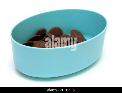 Bottoni di cioccolato al latte in un contenitore blu su sfondo bianco Foto Stock