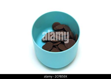 Bottoni di cioccolato al latte in un contenitore blu su sfondo bianco Foto Stock