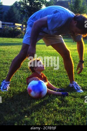 Ragazzo toddler giocare su erba con adulto Foto Stock