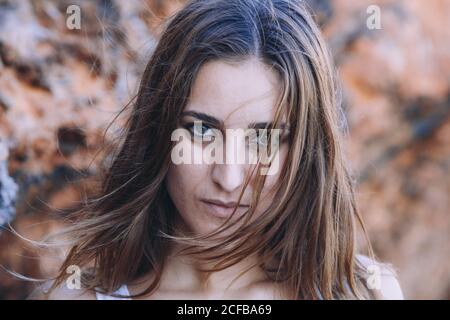 Primo piano ritratto di Donna in abiti casual appoggiato su parete rocciosa e guardando la macchina fotografica Foto Stock