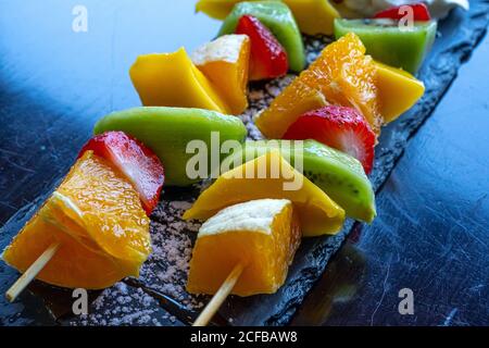 Kebab di frutta fatto di arance, fragole, Kiwi, Mango. Primo piano della macro. Messa a fuoco selettiva Foto Stock