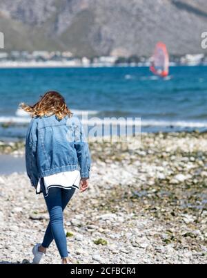 Giovane donna che cammina sulla riva del mare Foto Stock