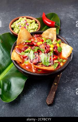 Zuppa messicana di fagioli neri con tortillas fritte fatte in casa totopos nachos servito con guacamole Foto Stock