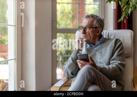 Senior uomo guardando fuori della finestra a casa Foto Stock