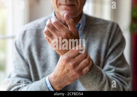 Uomo anziano con l'artrite sfregando le mani Foto Stock