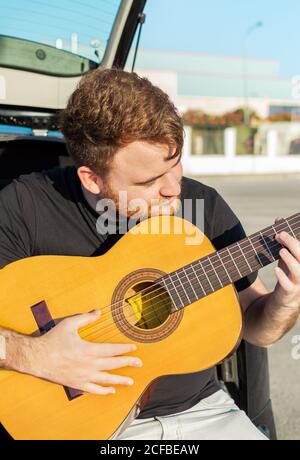 Ritratto di giovane redhead che suona la chitarra per strada. Foto Stock