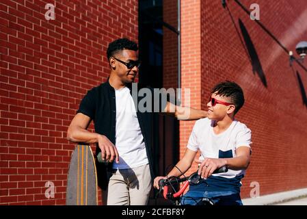 Sorridendo amici maschi neri con bicicletta e skateboard Foto Stock
