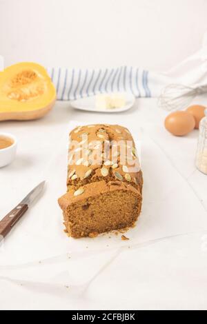 Pane fresco di zucca fatto in casa con purea di zucca, cannella, noce moscata e semi, posto su sfondo bianco. Foto Stock