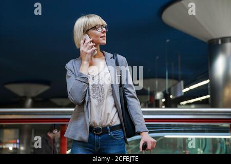 Donna d'affari con bagagli che parla al telefono Foto Stock